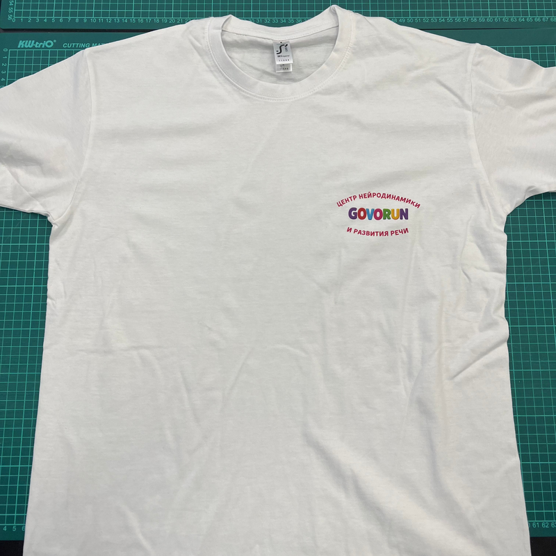 White t-shirt with colorful text on a green cutting mat