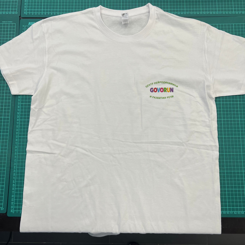 White t-shirt with colorful text on a green cutting mat